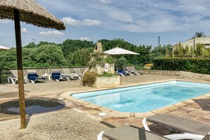 A swimming pool with lounge chairs and umbrellas, surrounded by greenery and a stone wall. - Two 18th-century country houses 'Can Gat Vell' with private pool, Wi-Fi, AC, fans (LLAMPAIES)