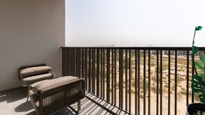 A balcony with a view of a desert landscape, a chair, and a potted plant. - MAG EYE 890 - Modern Studio Near Downtown (Meydan)