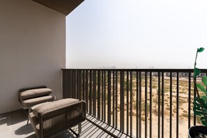 A balcony with a view of a desert landscape, a chair, and a potted plant. - MAG EYE 890 - Modern Studio Near Downtown (Meydan)