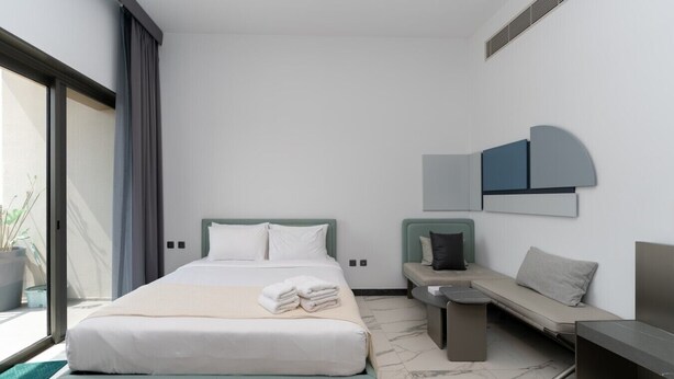 A modern hotel room with a bed, seating area, and a large window. - MAG EYE 890 - Modern Studio Near Downtown (Meydan)
