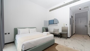 A modern hotel room with a bed, a seating area, and a door leading to another room. - MAG EYE 890 - Modern Studio Near Downtown (Meydan)