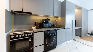 A modern kitchen with a built-in oven, microwave, and washing machine. - MAG EYE 890 - Modern Studio Near Downtown (Meydan)