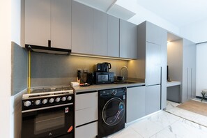 A modern kitchen with a built-in oven, microwave, and washing machine. - MAG EYE 890 - Modern Studio Near Downtown (Meydan)
