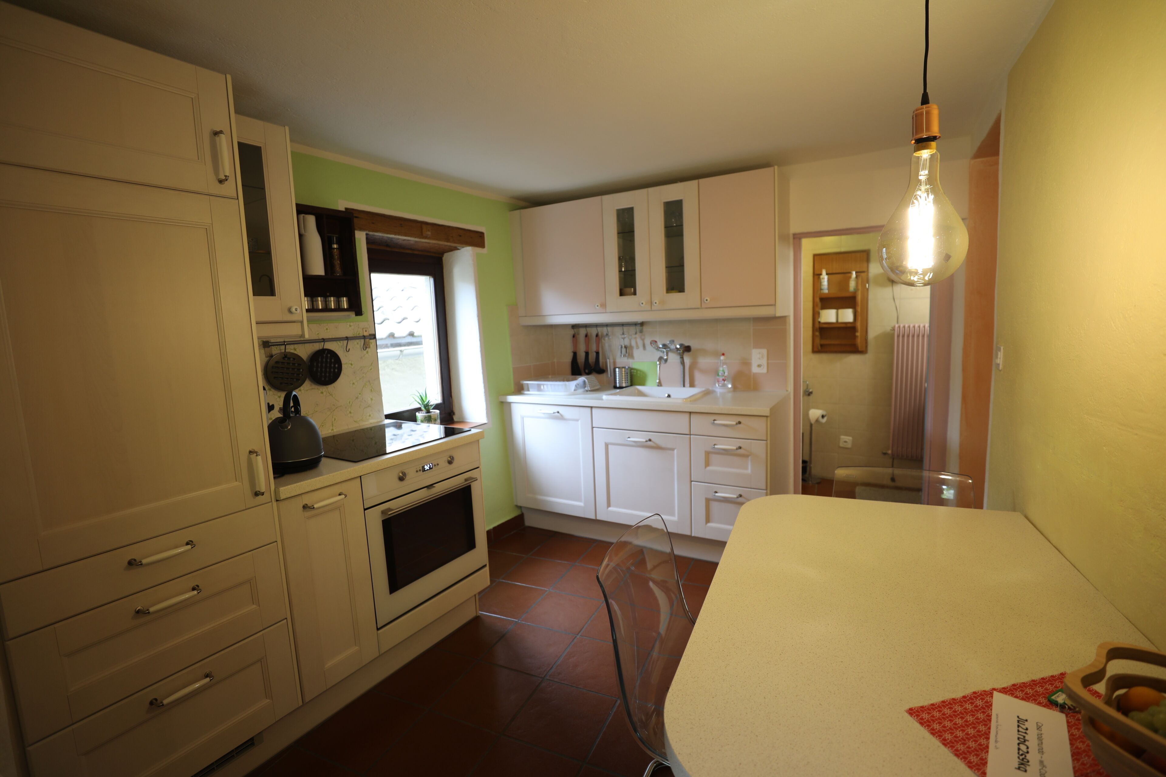 A compact kitchen with white cabinets, a stove, and a window.