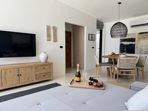 A modern living room with a flat-screen TV, wooden furniture, a dining area with wicker chairs, and a large painting on the wall. - Villa Ramay - Boutique Pool Villa - 5 Minutes to Fisherman's Village (Amphoe Ko Samui)