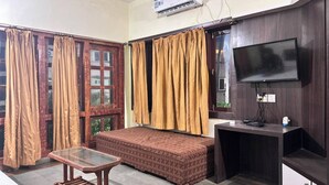 Una stanza con un letto, un tavolino in vetro, una panca, una televisione e un condizionatore d'aria.