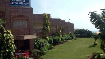 A building with a sign in a foreign language, a lawn, and red chairs outside.