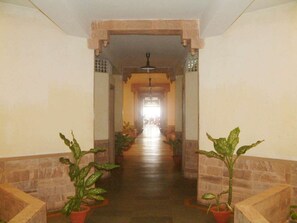 A corridor with potted plants on either side, leading to a bright area at the end. - Dalmia Resort - Puri (Puri)
