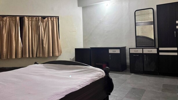A bedroom with a bed, a wardrobe, a mirror, and curtains. - Dalmia Resort - Puri (Puri)