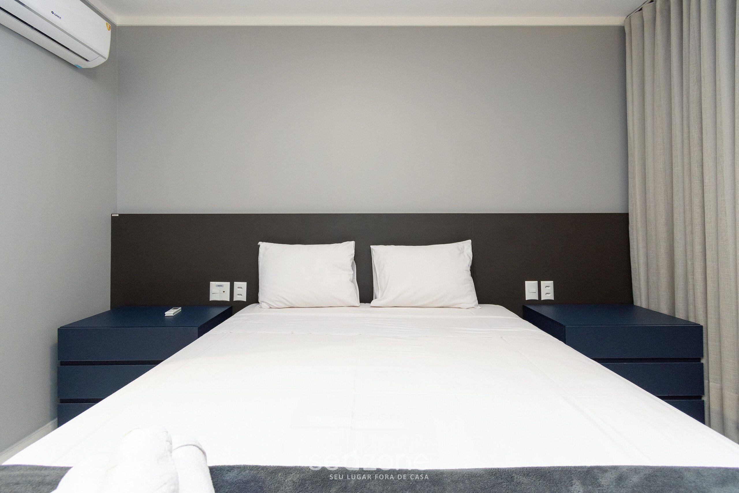 Een hotelkamer met een groot bed, twee nachtkastjes en een hoofdeinde.
