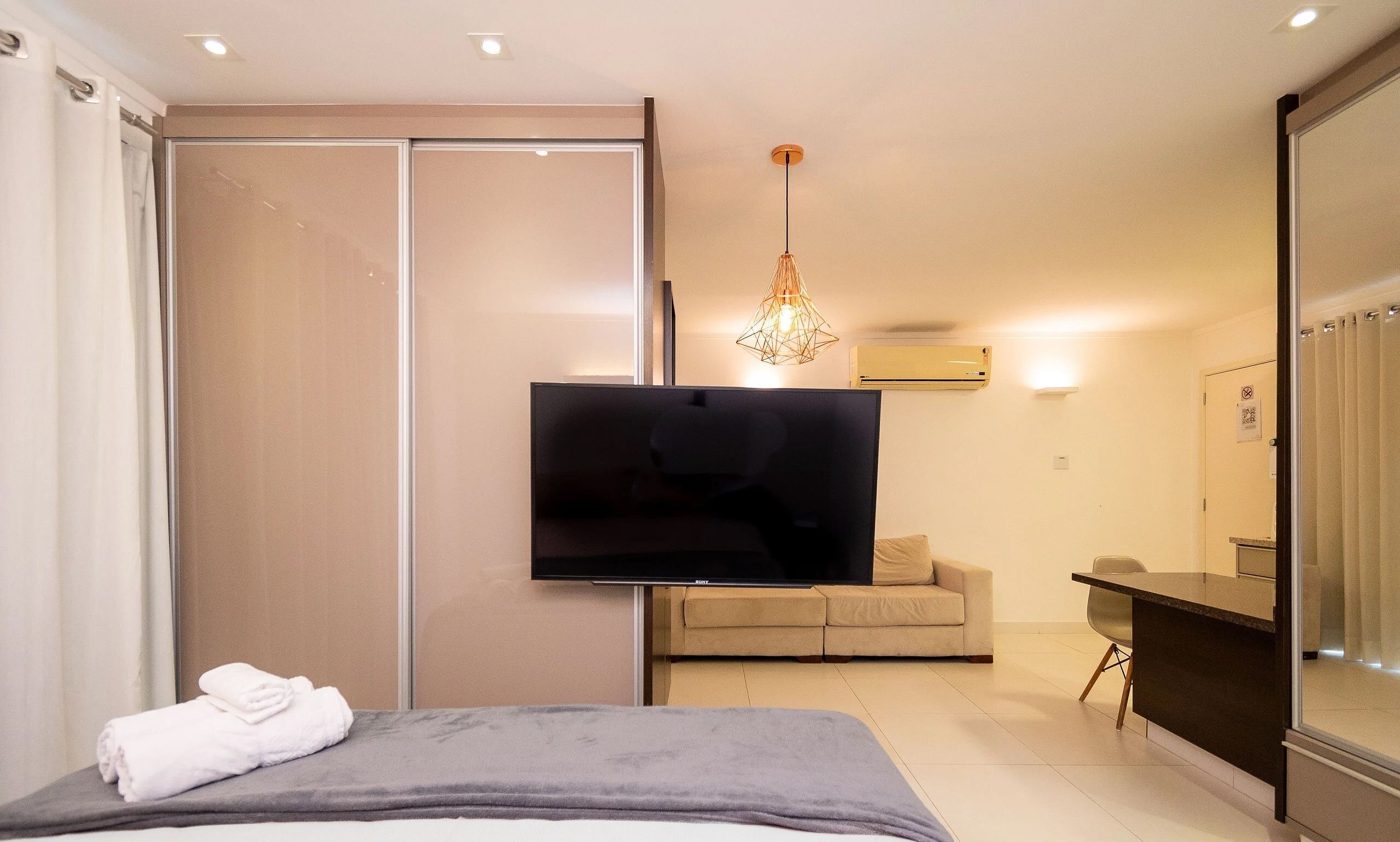 Een moderne hotelkamer met een bed, een flatscreen televisie, een bank en een eethoek.