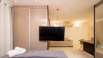 Une chambre d’hôtel moderne équipée d’un lit, d’un téléviseur à écran plat, d’un canapé et d’un coin repas.