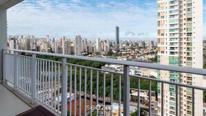 A high-rise building with multiple floors, a balcony with a white railing, and a cityscape with various buildings in the background. - Flat w/ gym in Setor Bueno - Wbu2405 (Goiânia)