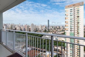 A high-rise building with multiple floors, a balcony with a white railing, and a cityscape with various buildings in the background. - Flat w/ gym in Setor Bueno - Wbu2405 (Goiânia)