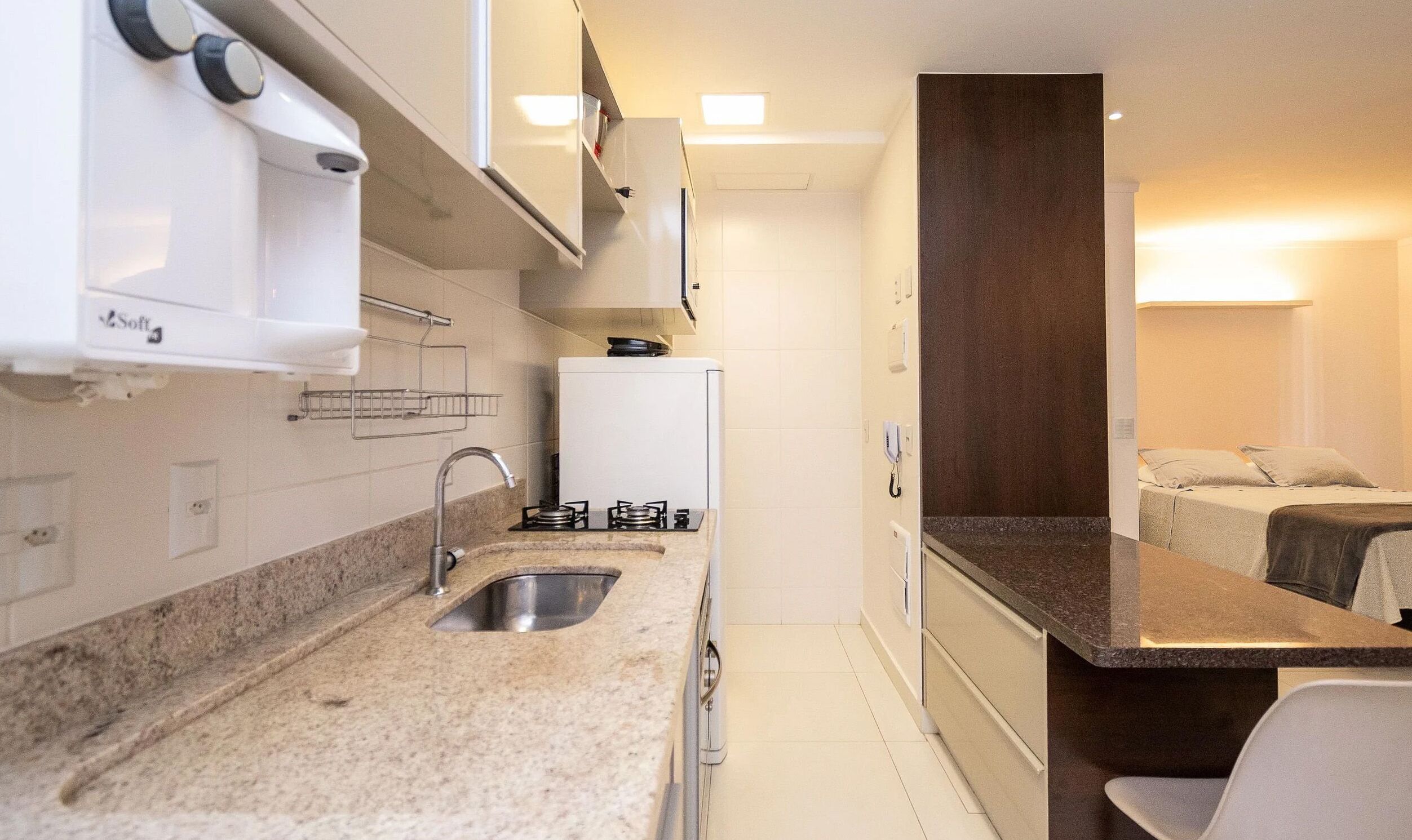 A compact kitchenette with a sink, stove, and a small refrigerator.