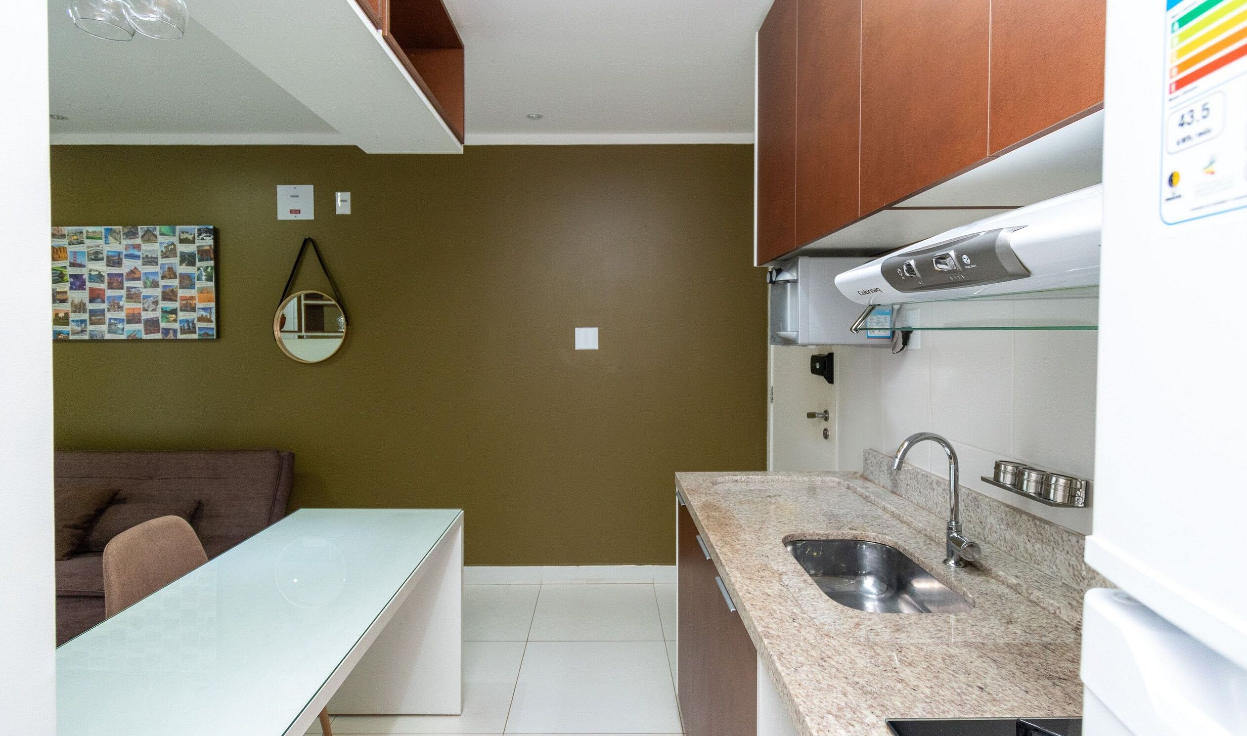A compact kitchen with a granite countertop, stainless steel sink, and a white refrigerator.