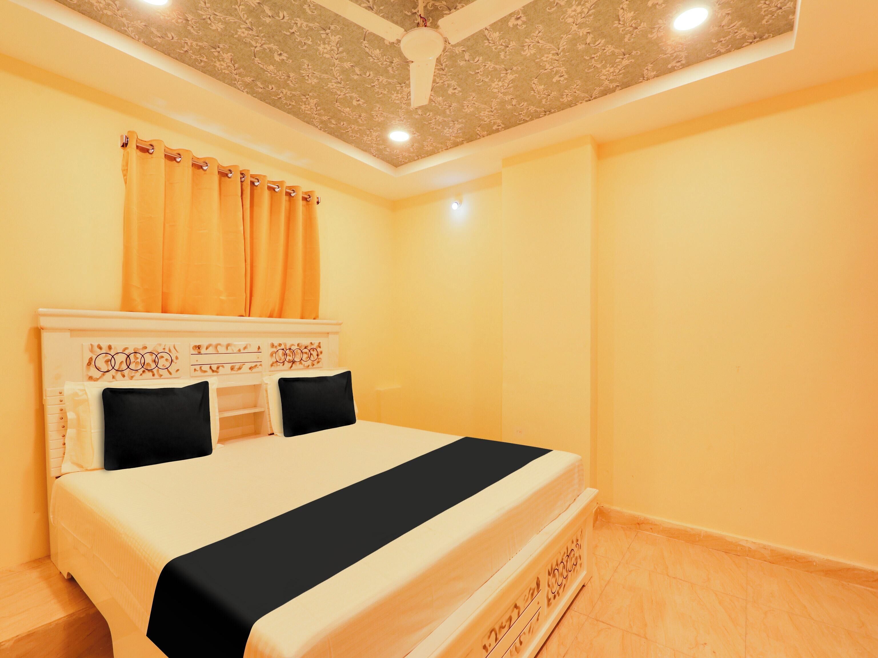 Una habitación de hotel con cama, ventilador de techo y ventana con cortinas.