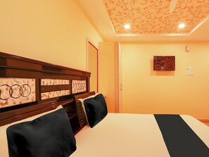 A hotel room with a bed, a headboard with circular designs, a door, and a wall-mounted light fixture. - Super Collection O Bommarilu Warangal (Warangal)