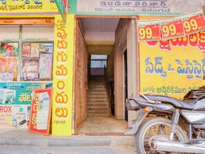 A storefront with a staircase leading to the entrance, a motorcycle parked outside, and various signs and advertisements. - Super Collection O Bommarilu Warangal (Warangal)
