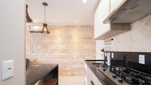 Een moderne keuken met een steenspetsel, roestvrijstalen apparatuur en een hanglamp.