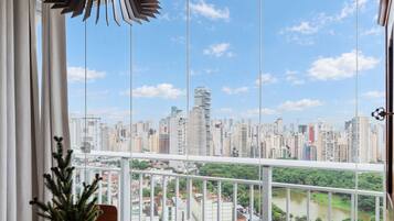 Un balcón con vista a la ciudad, una planta en maceta y una lámpara colgante.