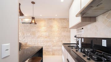 Cocina moderna con salpicadero de piedra, electrodomésticos de acero inoxidable y una lámpara colgante.