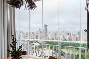 Ein Balkon mit Blick auf die Stadt, einem Blumentopf und einem Tisch.