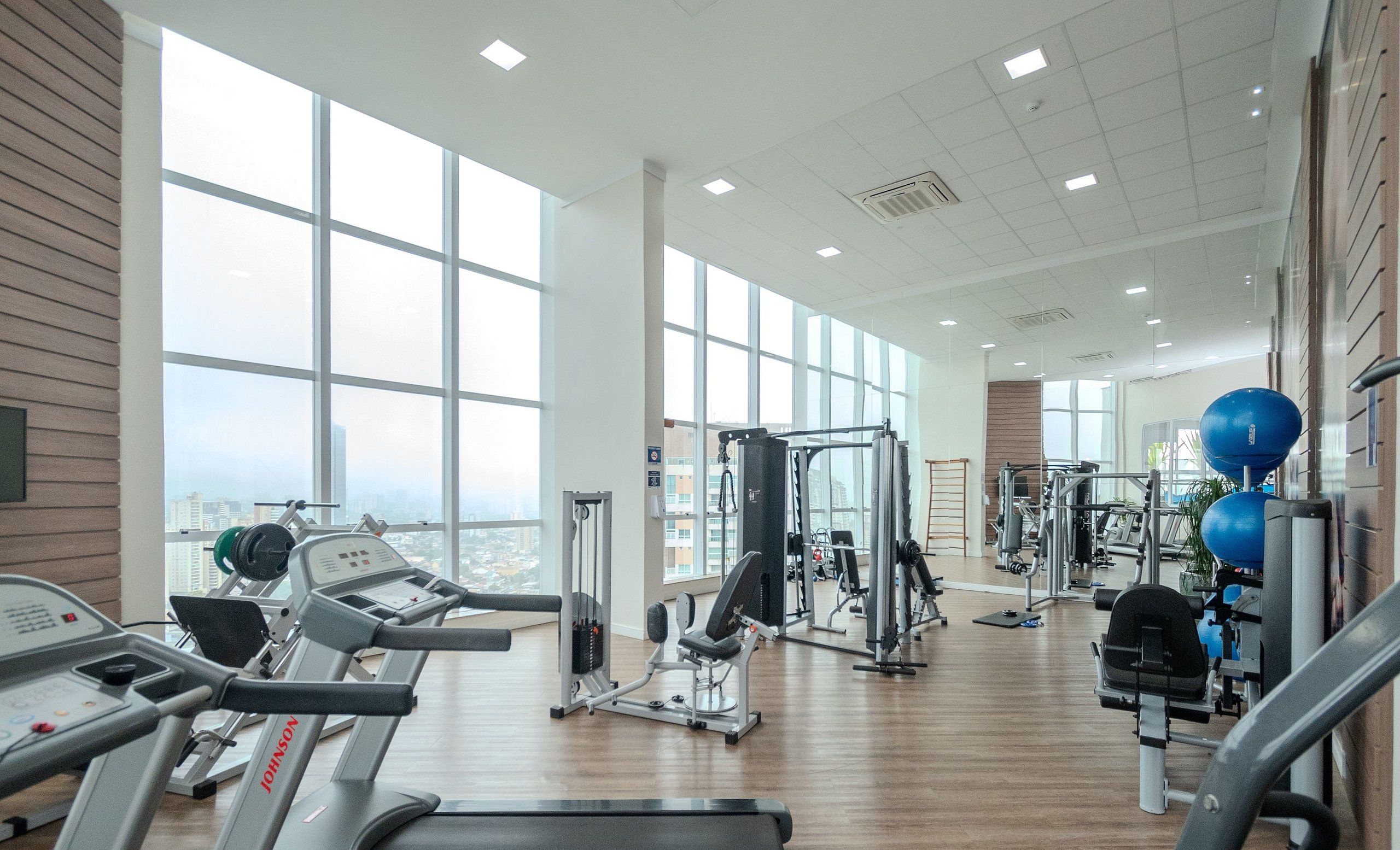 Une salle de sport spacieuse équipée de tapis de course, d’appareils de musculation et de ballons d’exercice.