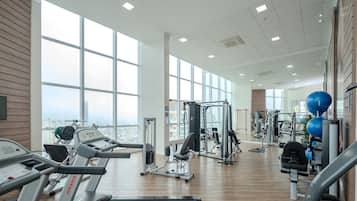 Un gimnasio amplio con cintas de correr, máquinas de pesas y pelotas de ejercicio.