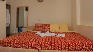 Una habitación de hotel con cama, mesita de noche, espejo y armario.