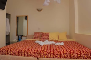 A hotel room with a bed, a bedside table, a mirror, and a wardrobe.