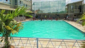 Una piscina con gente alrededor, rodeada de edificios.