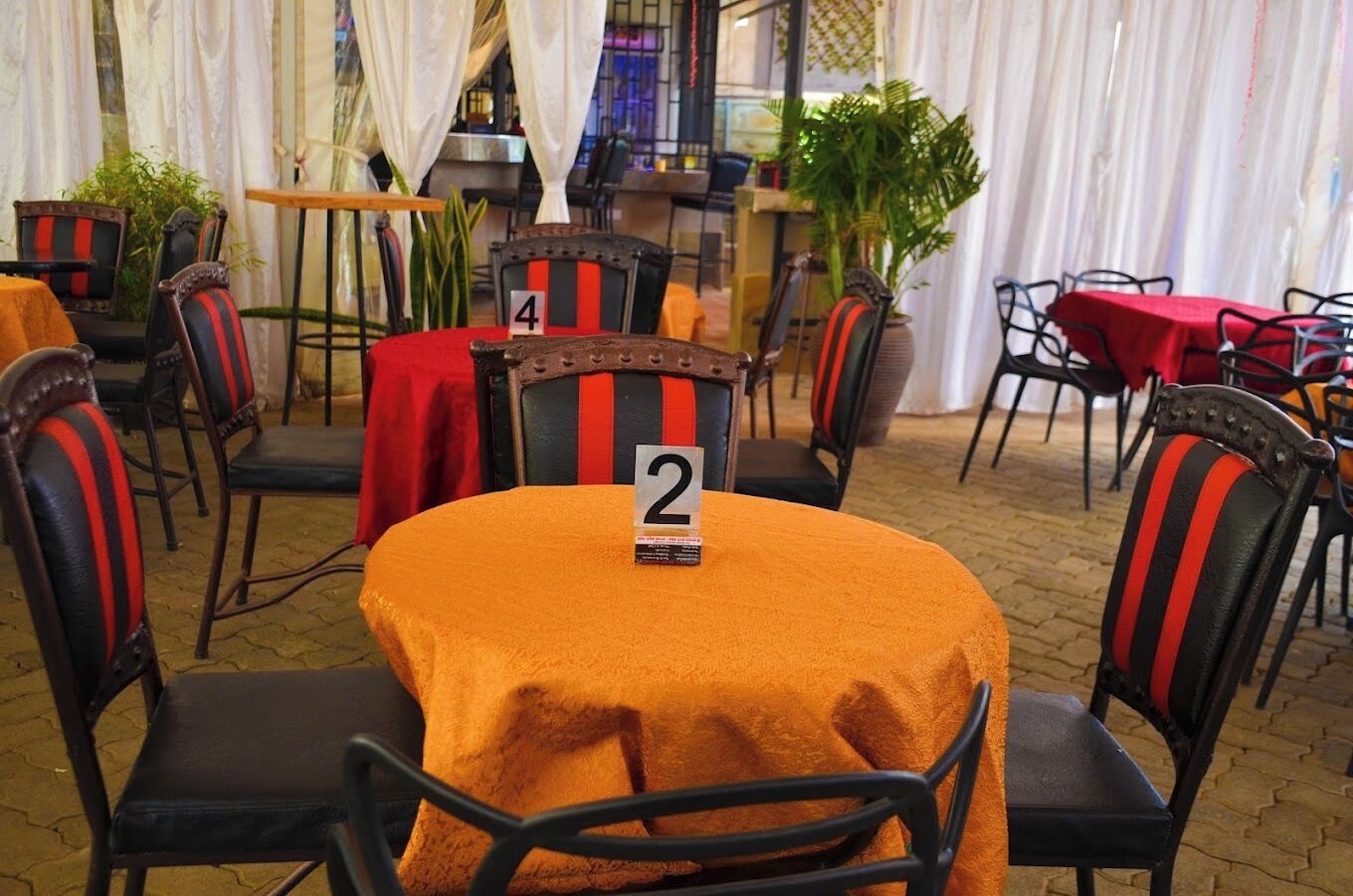 Un restaurante con mesas redondas, sillas numeradas y piso de ladrillo.