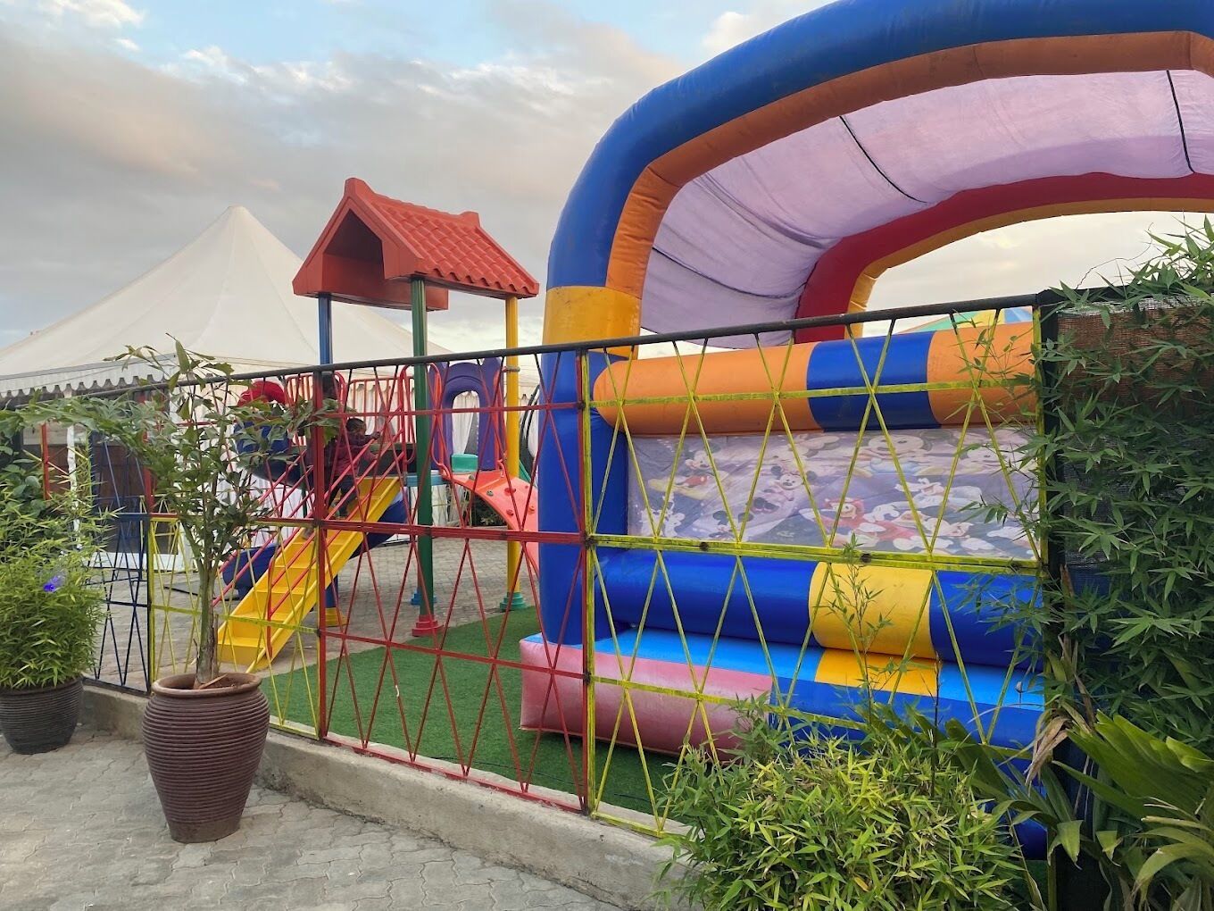 Un parque infantil con tobogán, estructuras para escalar y una gran zona de inflables.