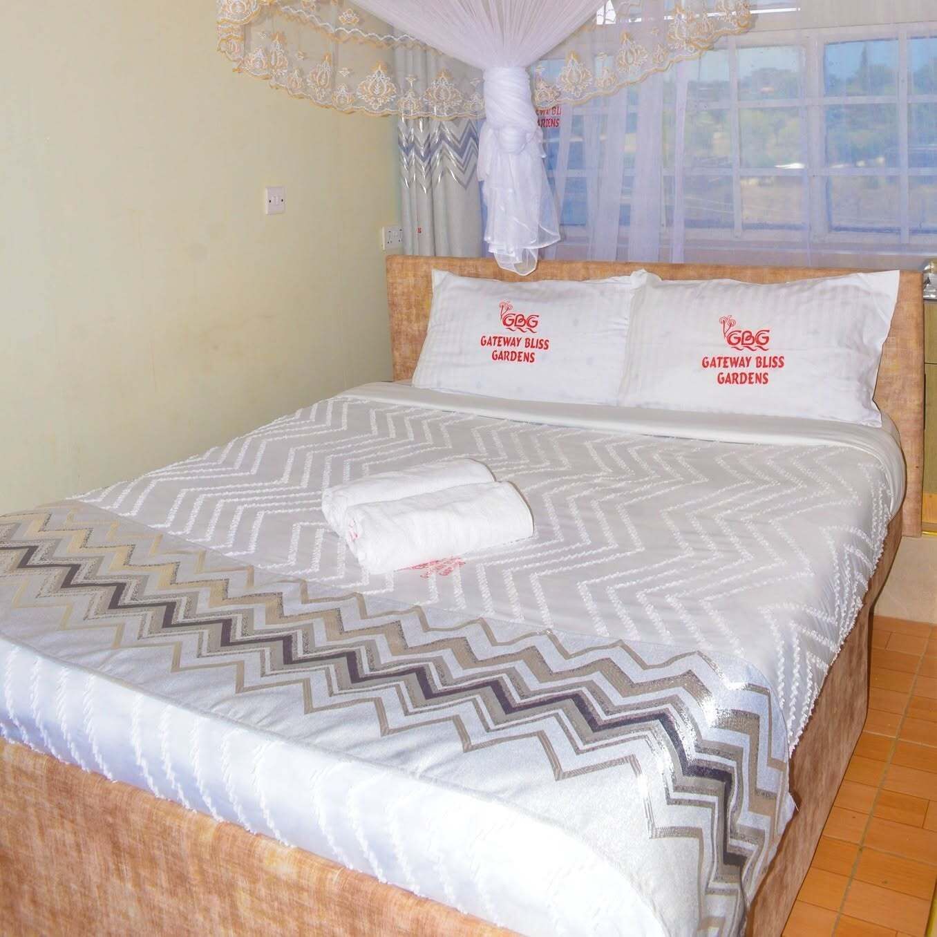 Una habitación de hotel con cama, almohadas y dosel.