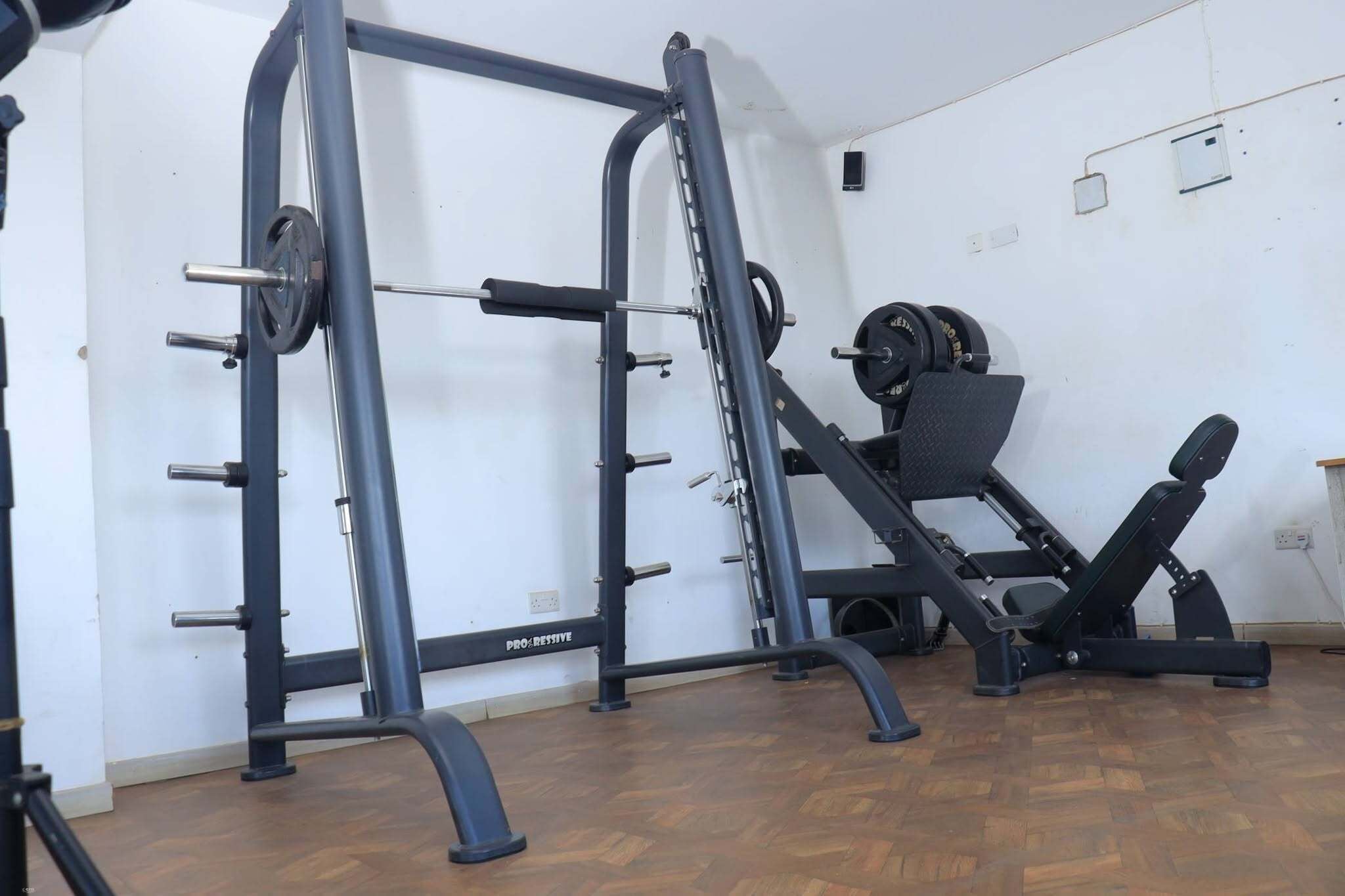 A gym with a squat rack, bench press, and weight plates.