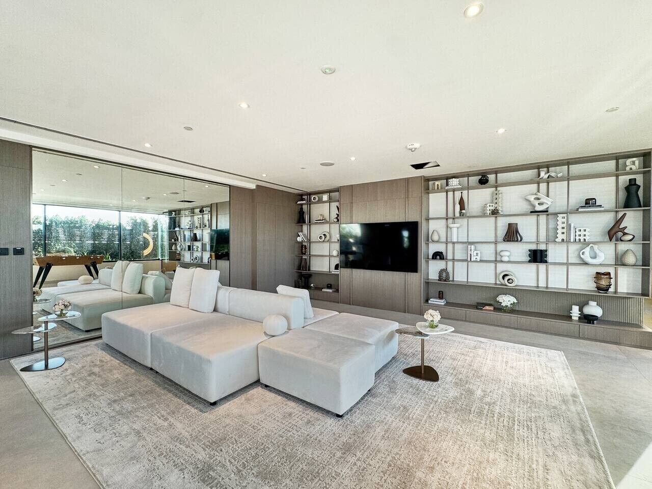 Un soggiorno moderno con un divano componibile, una TV a schermo piatto e un mobile decorativo a parete.
