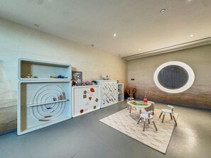 Ein modernes Interieur mit einem runden Tisch in der Mitte, weißen Schränken mit geometrischen Mustern und einer großen, runden Wandgestaltung.