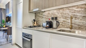 A modern kitchen with a marble backsplash, stainless steel appliances, and a sleek faucet. - Chic Studio | Pool View Balcony | Avelon Arjan (Dubai)