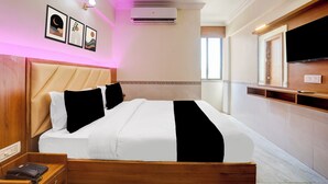 A hotel room with a bed, bedside table, a telephone, a wall-mounted TV, and framed artwork. - Super Collection O Ahmedabad Airport (Ahmedabad)