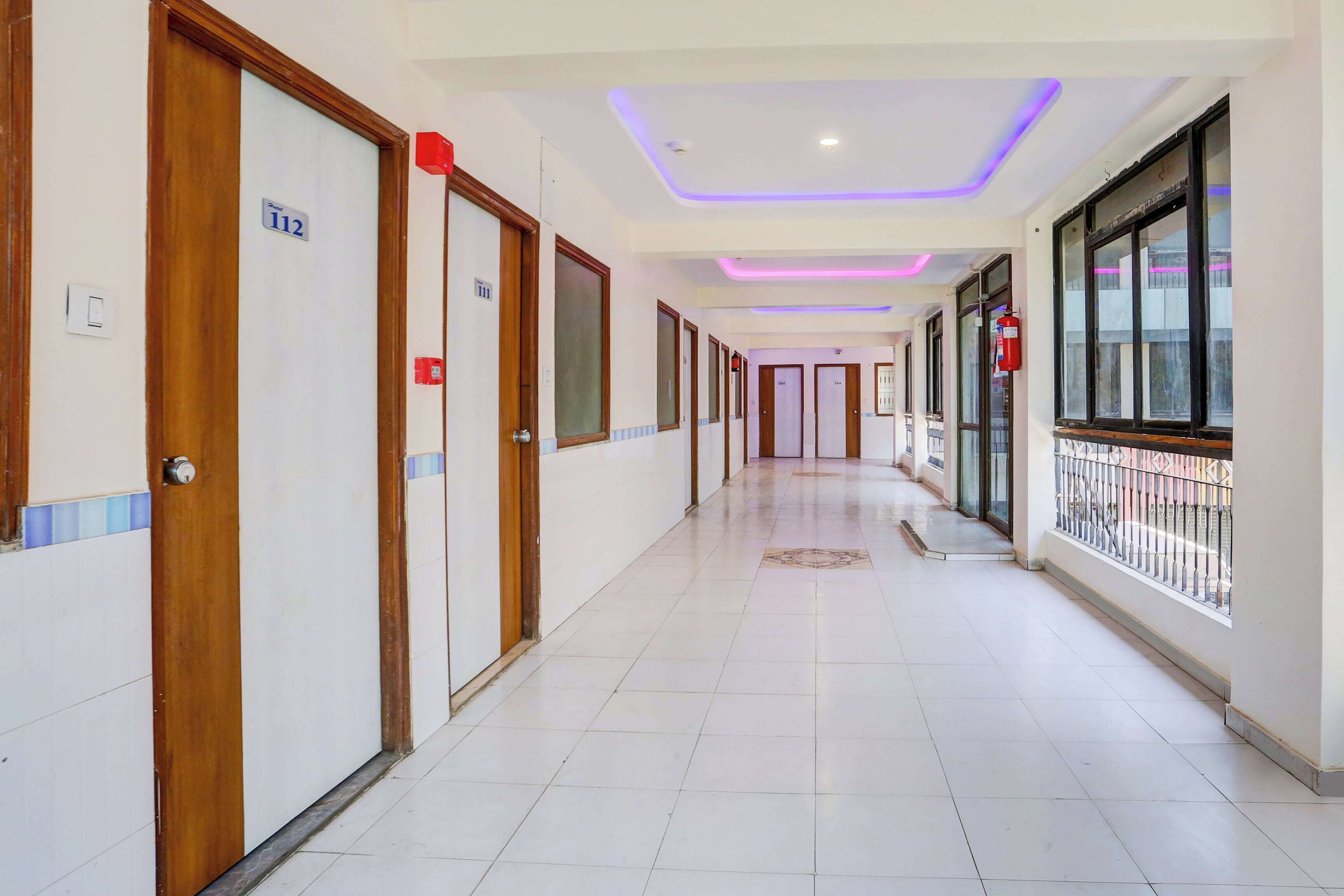 A hotel corridor with doors numbered 112 and 111, a tiled floor, and a balcony with a metal railing.