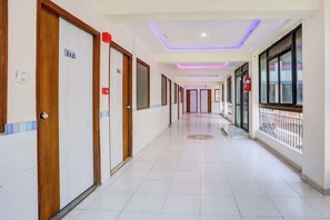 A hotel corridor with doors numbered 112 and 111, a tiled floor, and a balcony with a metal railing. - Super Collection O Ahmedabad Airport (Ahmedabad)