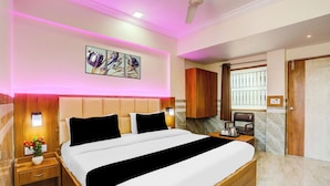 A hotel room with a large bed, a nightstand, a desk with a chair, a wardrobe, and a bathroom visible through a door. - Super Collection O Ahmedabad Airport (Ahmedabad)