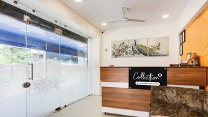 A reception area with a glass door, a wooden reception desk, and a wall-mounted artwork. - Super Collection O Ahmedabad Airport (Ahmedabad)