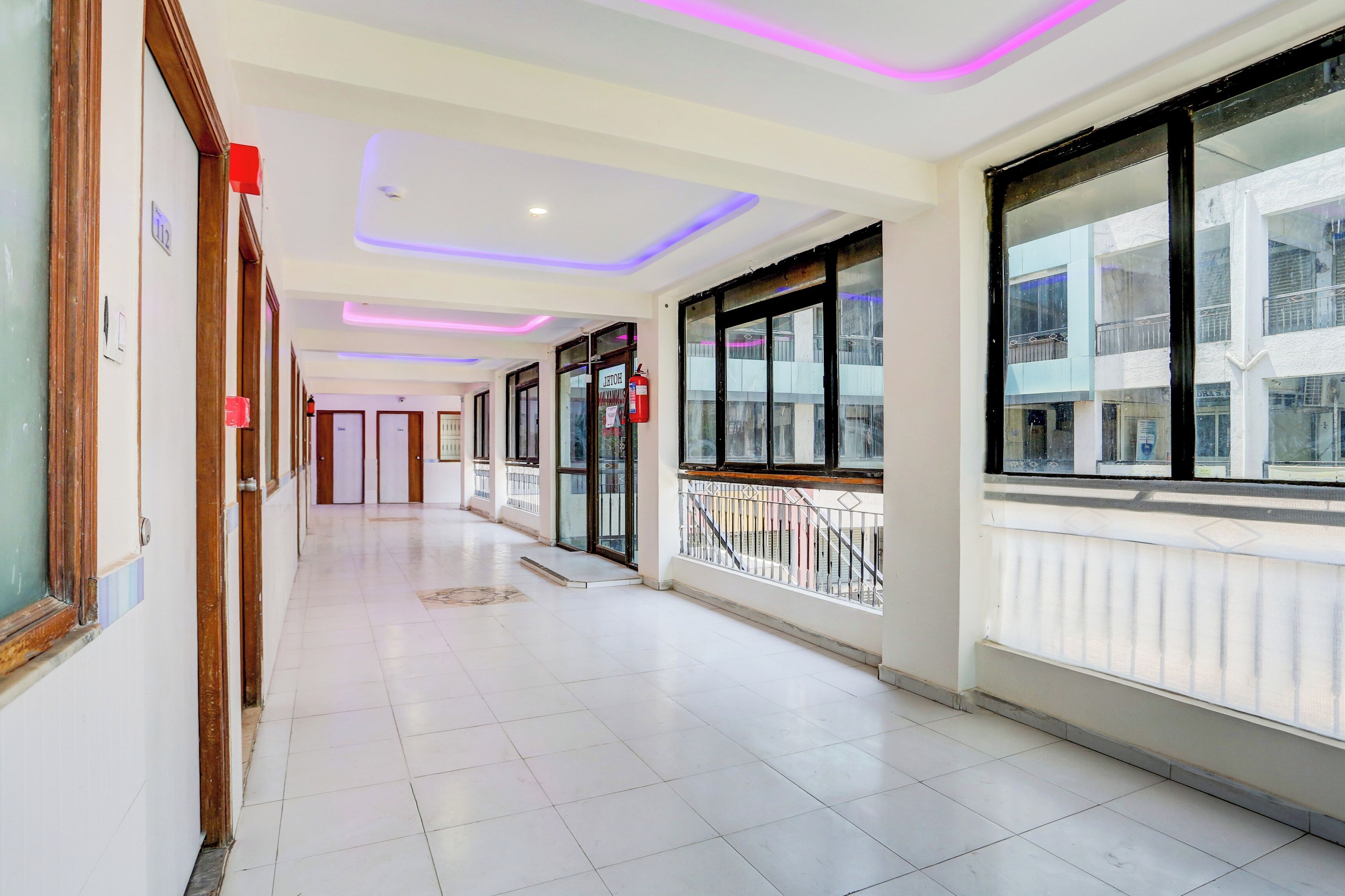 A hotel corridor with a tiled floor, doors, and windows.