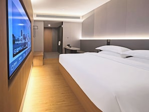 A modern hotel room with a large bed, a bedside table, a TV mounted on the wall, and a wooden floor. - Homtel by Poltton (Guangzhou Shenzhou Road Metro Station Lingnan College Branch) (Guangzhou)