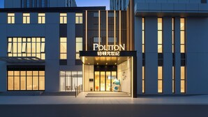 Un hotel moderno con una entrada destacada, ventanas amplias y un cartel que dice 'POULTON'.