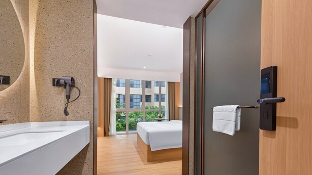 Habitación de hotel con un espejo grande, un secador de pelo, una cama y vistas a un edificio por la ventana.