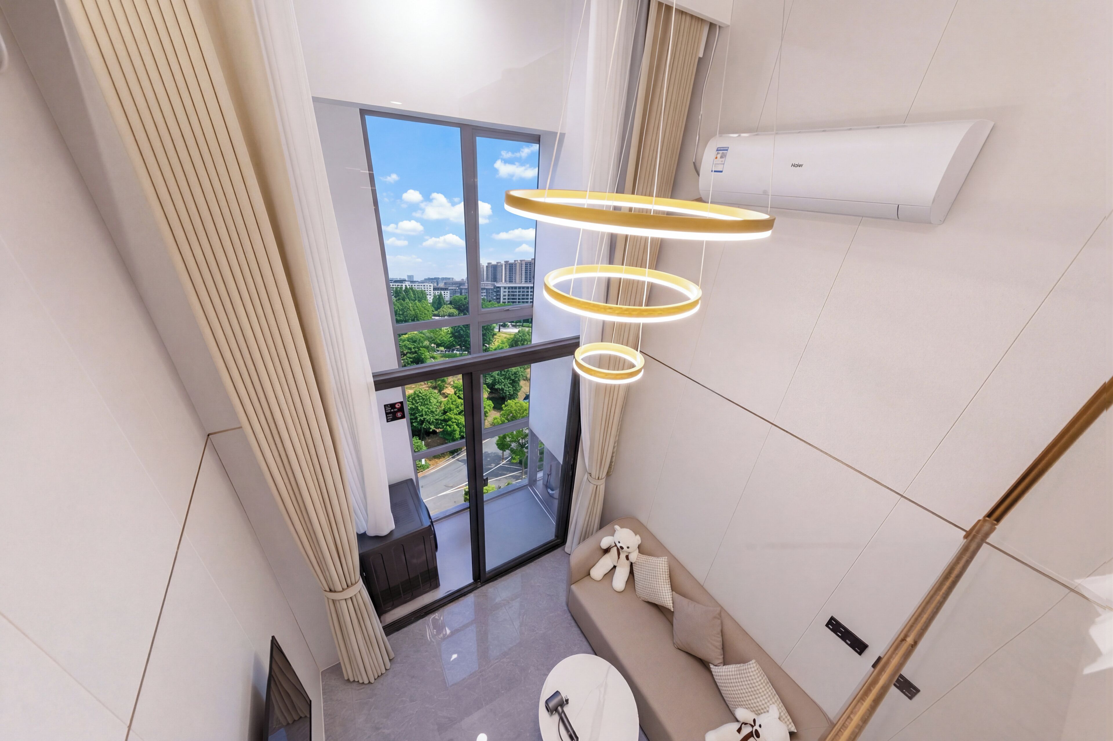 Un interior modern amb un sofà, una taula rodona i una vista a través d'una porta de vidre a una zona exterior.