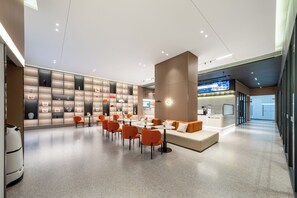 A modern hotel lobby with a central seating area, a wall of framed artwork, and a reception desk. - Homtel by Poltton (Guangzhou Shenzhou Road Metro Station Lingnan College Branch) (Guangzhou)